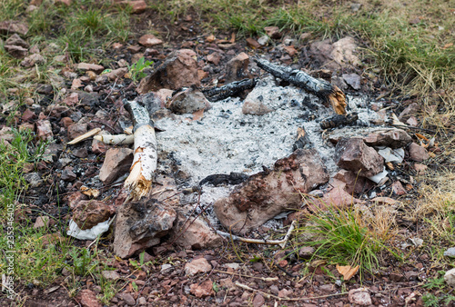 extinguished fireplace with ash and remains of wood lined with stones on the ground in a circle