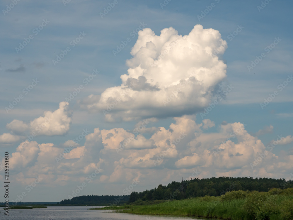 clouds above lake and green forest