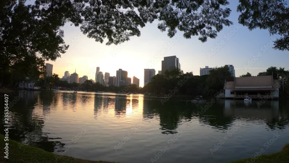 4k A time lapse of the large orange sunset as the massive sun sets into the horizon above water building the city 4k A time lapse of the large orange sunset as the massive sun sets into the horizon above water building the city