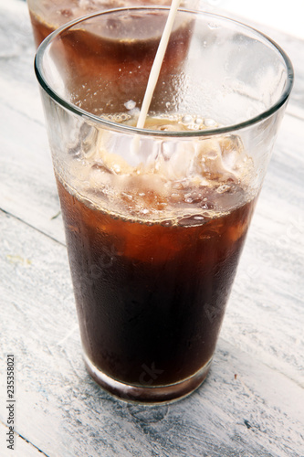 Ice coffee on a rustic table with cream being poured into it showing the texture and refreshing look of the drink