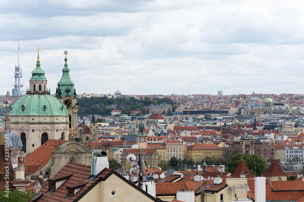 Prague panorama with colorful rooftops on a cloudy day, with The Church of St. Nicholas and Zizkov television tower in the distance
