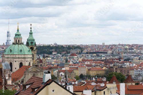 Prague panorama with colorful rooftops on a cloudy day, with The Church of St. Nicholas and Zizkov television tower in the distance