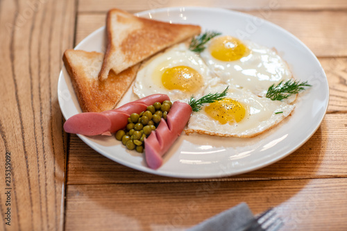 Breakfast food. American style breakfast with fried eggs  sausage  green peas and toast. The concept of a healthy morning.