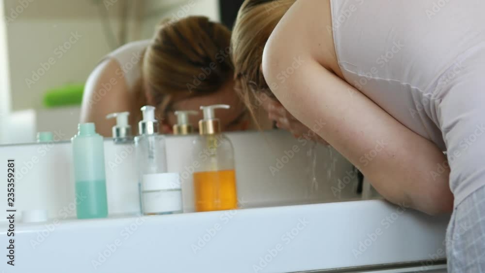 Waman washing her face in bathroom. Waman washing her face in bathroom.