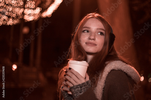 The portrait of an young smiling redhear lady on the evening wearing earmuffs photo