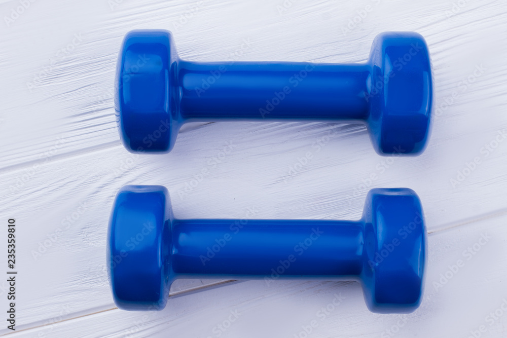 Pair of blue dumbbells on wooden background. Gym workout equipment. For good health and strong body. Pair of blue dumbbells on wooden background. Gym workout equipment. For good health and strong body.