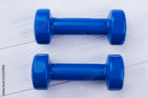 Pair of blue dumbbells on wooden background. Gym workout equipment. For good health and strong body.