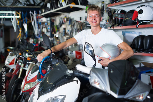 Cheerful male is sitting on the motorbike with helmet
