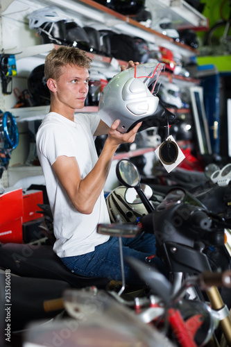 Young motorcyclist choosing new helmet for motorcycle