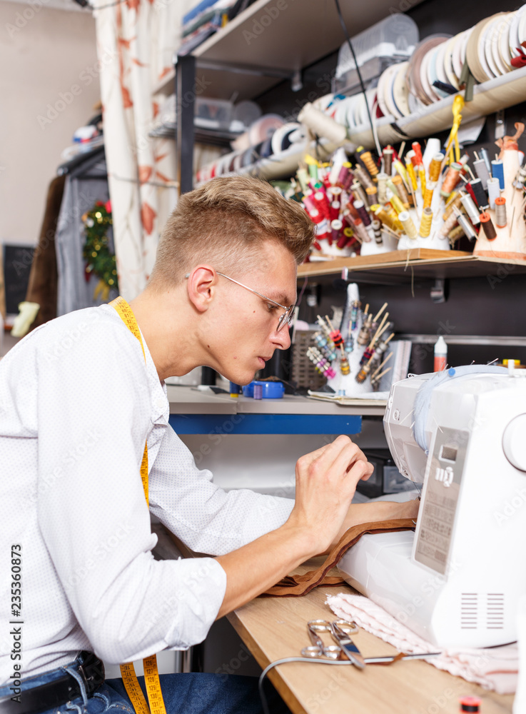 Obraz premium Dressmaker making clothes with sewing machine