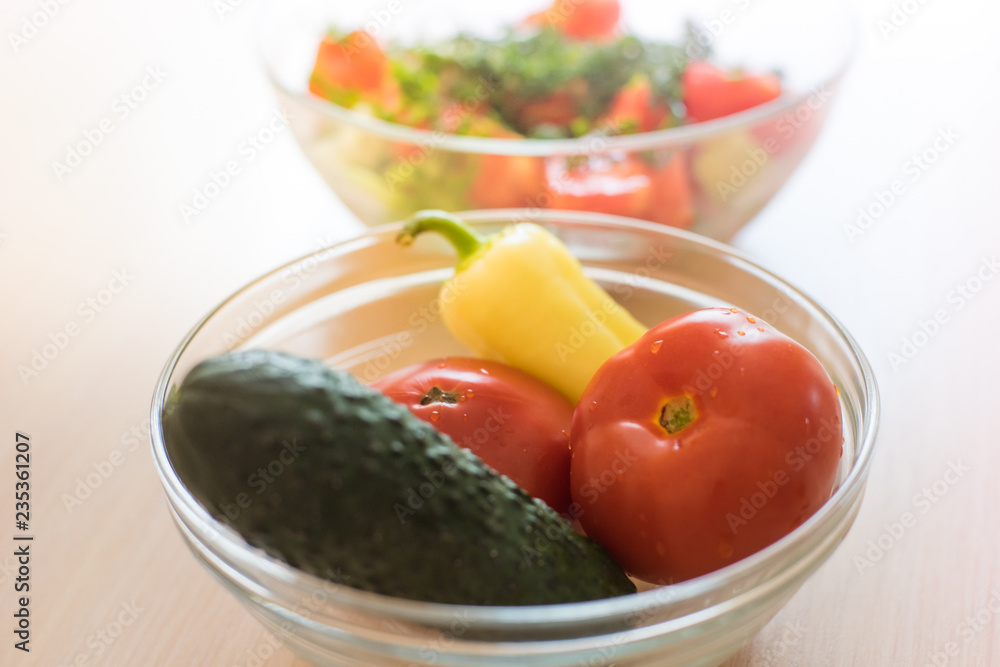 tomatoes, cucumber and pepper in a glass bowl closeup.