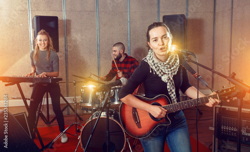 Attractive female soloist playing guitar and singing with her mu photo