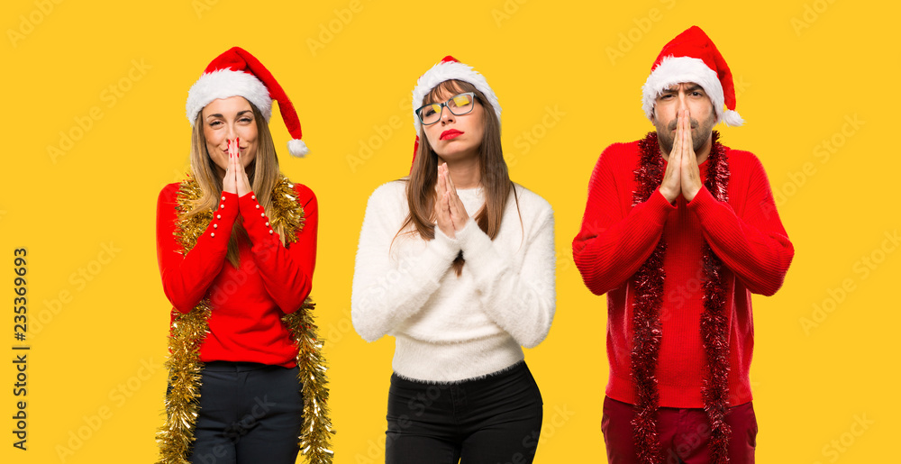 Fototapeta premium A group of people Blonde woman dressed up for christmas holidays keeps palm together. Person asks for something on yellow background
