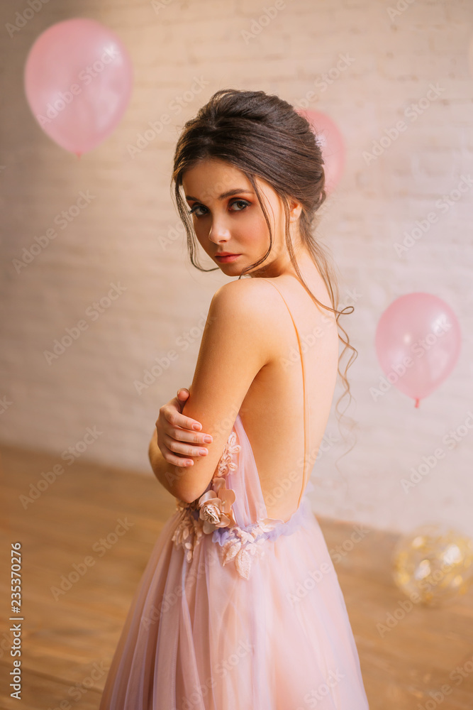 Φωτογραφία attractive young girl with dark hair in a gorgeous hairstyle, dressed in a long gentle pink with a purple dress with an open back