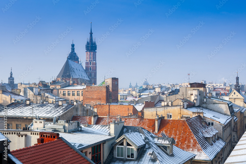 Fototapeta premium Krakow in Christmas time, aerial view on snowy roofs in central part of city. St. Mary's Basilica on Main Square. Poland. Europe.