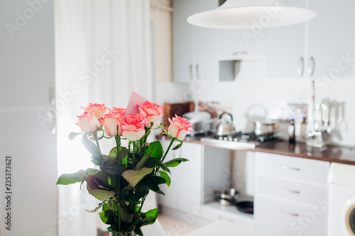 Bouquet of roses with card left on kitchen. Modern kitchen design. Interior of kitchen decorated with flowers. © maryviolet