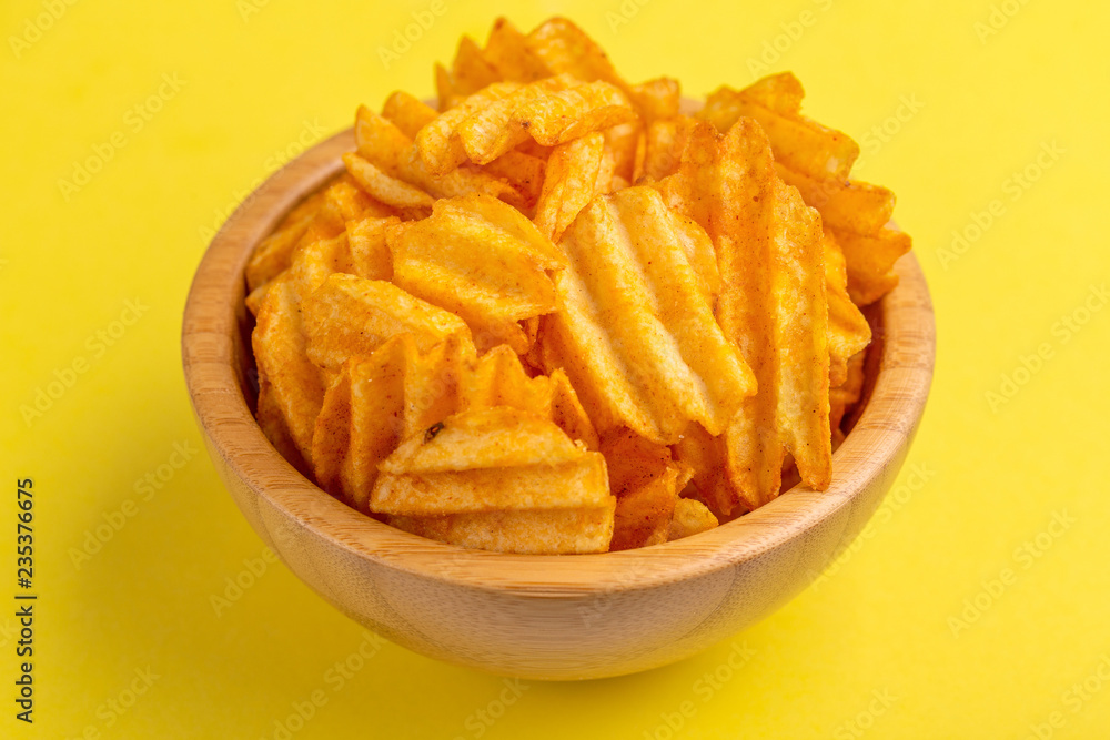 Crispy corrugated potato chips in wooden bowl Crispy corrugated potato chips in wooden bowl