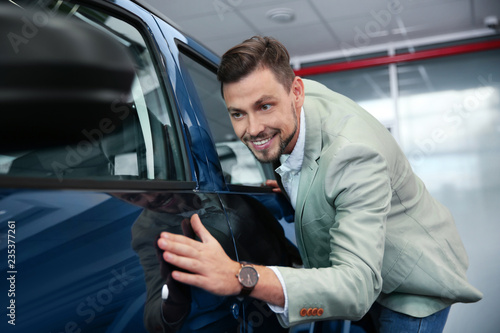 Man near new car in modern auto dealership