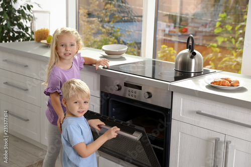 Little kids baking cookies in oven at home