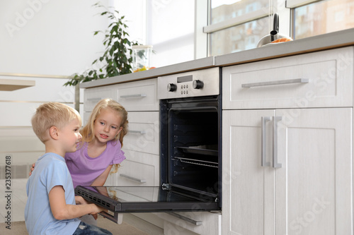 Little kids baking something in oven at home