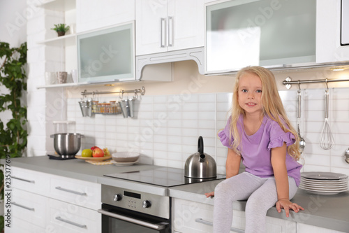 Cute little girl near oven in kitchen