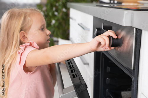 Little girl baking something in oven at home