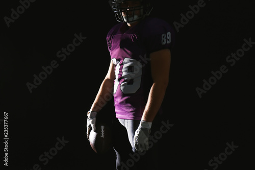 American football player with ball on dark background