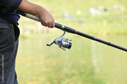Man fishing alone at riverside on sunny day, closeup