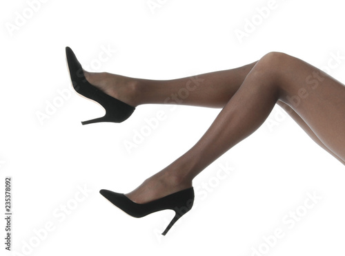 Legs of beautiful young woman in tights and high-heeled shoes on white background  closeup