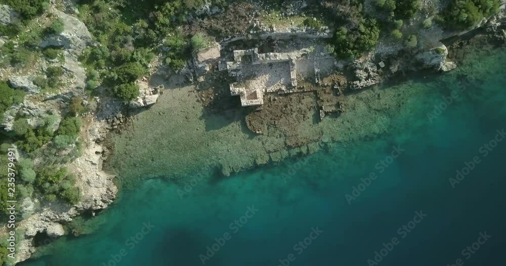 Twisting descending bird's eye aerial drone view camera straight down below low over clear turquoise water, harbor and ancient sunken city ruins of Kekova Island in Turkey. 4k at 23.97fps Twisting descending bird's eye aerial drone view camera straight down below low over clear turquoise water, harbor and ancient sunken city ruins of Kekova Island in Turkey. 4k at 23.97fps