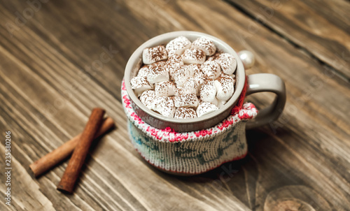 Cappuccino with marshmallows in a mug on a woolen scarf