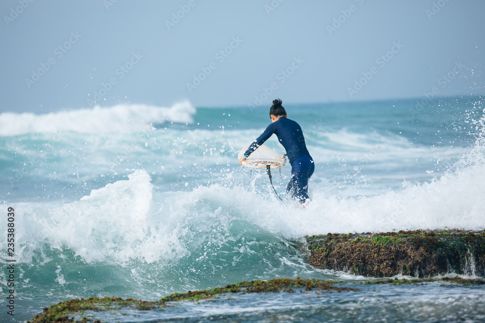 Woman surfer with surfboard going to surf the big waves Woman surfer with surfboard going to surf the big waves