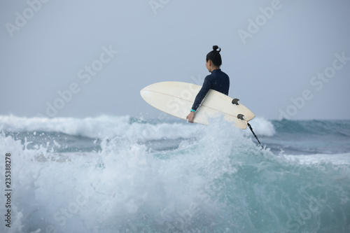 Woman surfer with surfboard going to surf the big waves