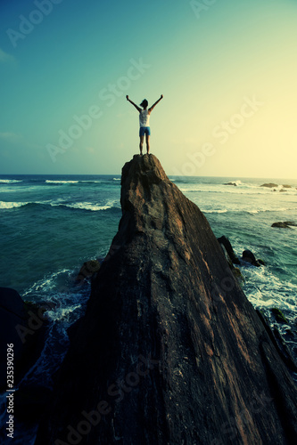 Canvas Print Freedom young woman outstretched arms on seaside rock cliff edge