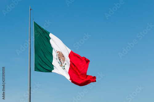 Giant waving flag of Mexico with a blue sky. photo