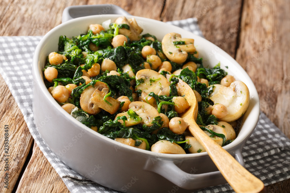 Delicious braised chickpeas with spinach and mushrooms closeup in a bowl. horizontal Delicious braised chickpeas with spinach and mushrooms closeup in a bowl. horizontal