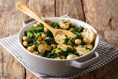 Stewed chickpea salad with spinach and champignons close-up in a bowl. horizontal