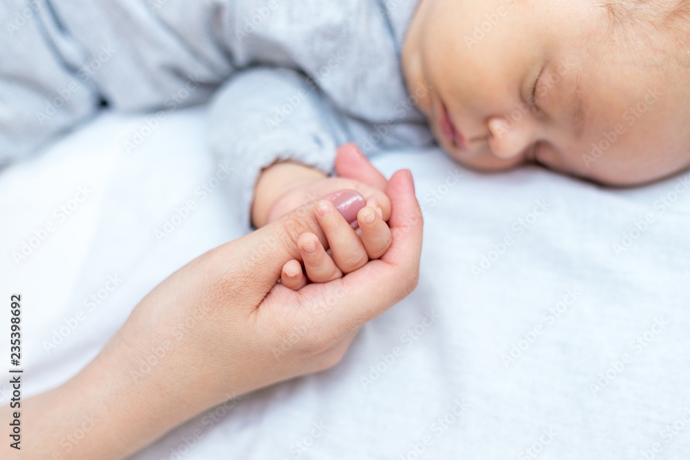 Young mother holding her newborn child hand Young mother holding her newborn child hand