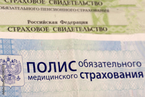 Close-up of Russian health insurance policy and Russian passport and a few pills on blue background .