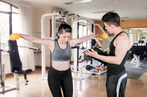 Woman exercise with her trainer in fitness center