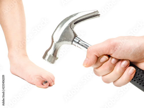 Male hand holding hammer over child's foot with blue big toe nail