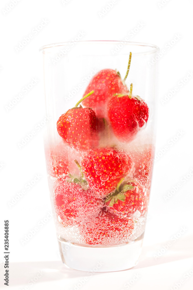 Pouring water on fresh strawberry with dancing bubbles in tall glass isolated on white background. Pouring water on fresh strawberry with dancing bubbles in tall glass isolated on white background.