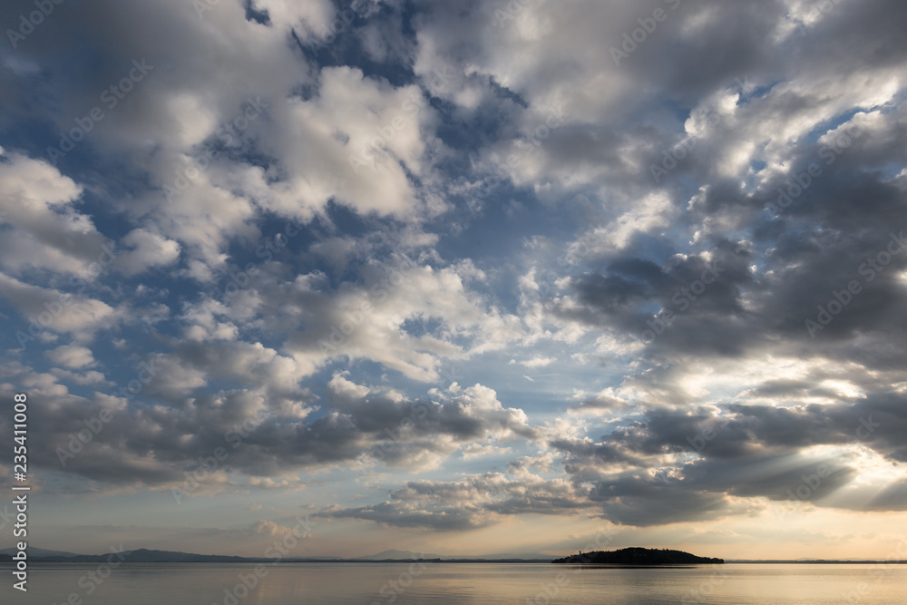 Trasimeno lake (Umbria, Italy) with big clouds at sunset above an island and blue sky