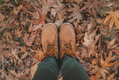 Conceptual image of legs in boots on the autumn leaves.