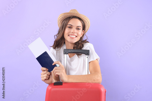 Young tourist girl in summer casual clothes, with sunglasses, red suitcase, passport isolated on purple background.