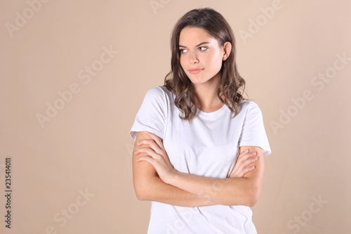 Young woman in casual clothing wondering and screaming isolated over beige background.