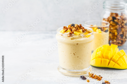 Mango smoothie with granola and coconut in a jar.