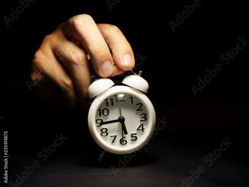 Time management. Hand is holding alarm clock.