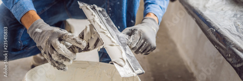 Принти на полотні master is applying white putty on a wall and smearing by putty knife in a room o