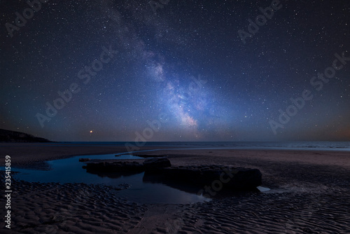Vibrant Milky Way composite image over landscape of Dunraven Bay in Wales